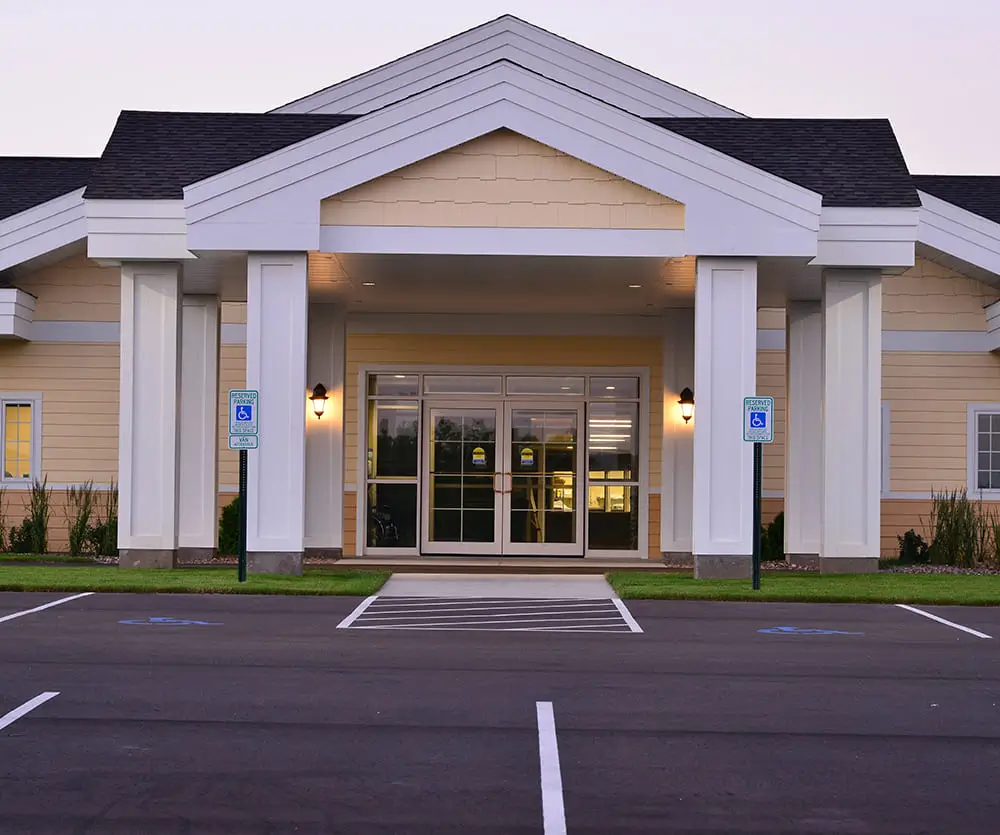 A single-story building with a large entrance and columns, featuring accessible parking spaces in the foreground.